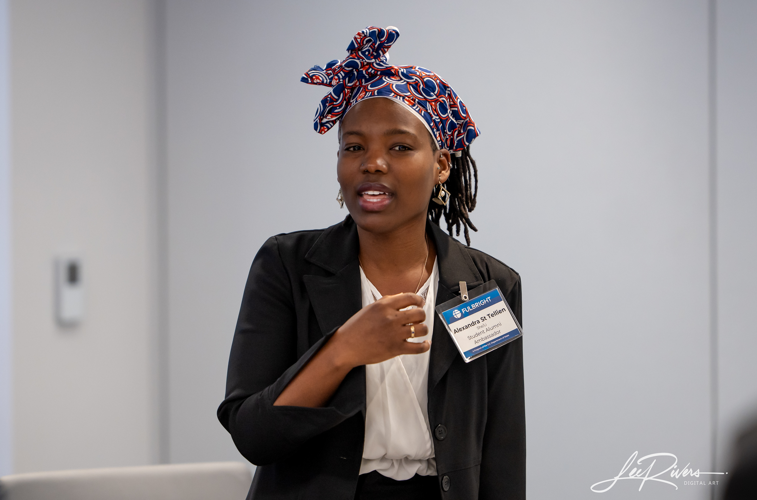 A medium shot of Alexandra St. Tellien speaking. She is wearing business attire and a Fulbright Alumni Ambassador bage.